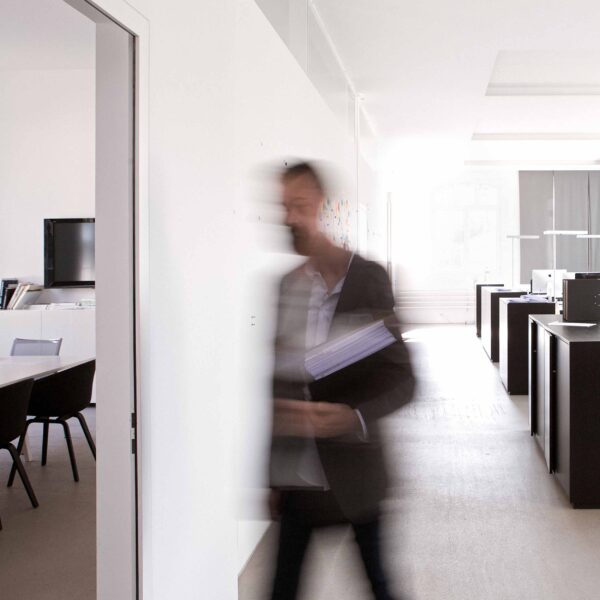 Mann trägt Ordner ins Sitzungszimmer