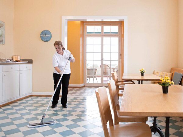 Eine Mitarbeiterin reinigt den Frühstücksraum